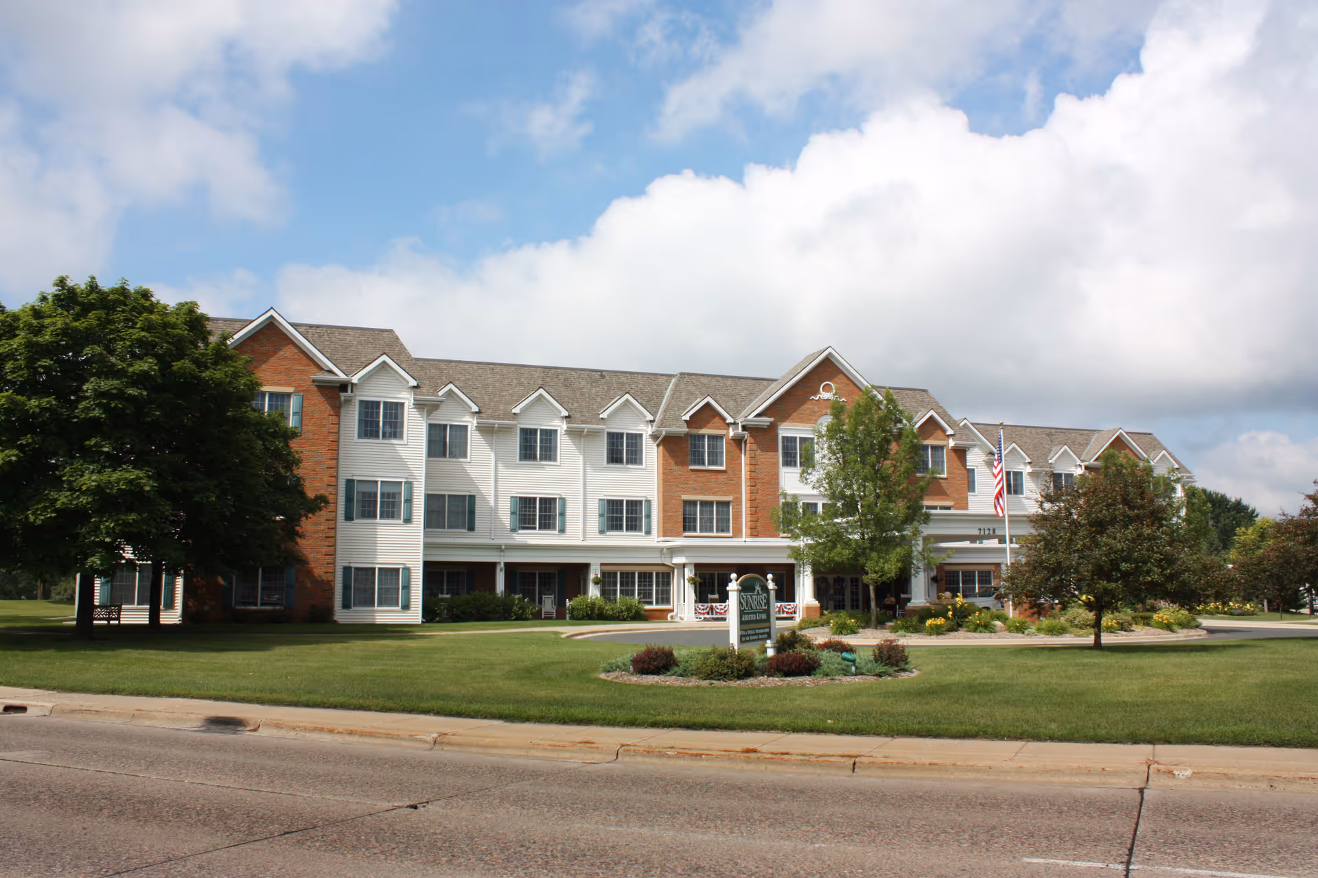 Exterior view of Sunrise of Edina facility with brick and white siding, landscaped lawn.