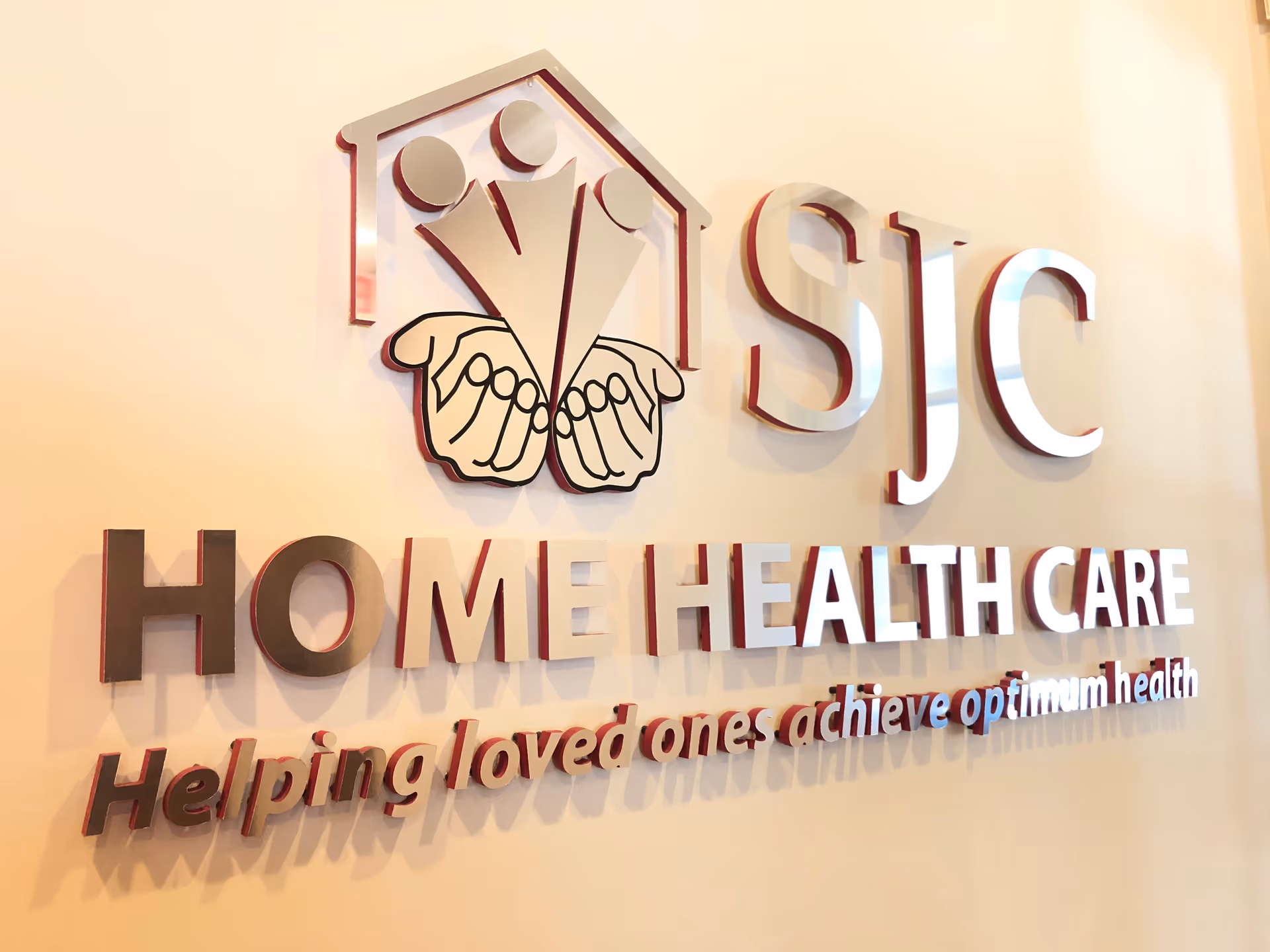 SJC Home Health Care sign with logo on a beige interior wall.