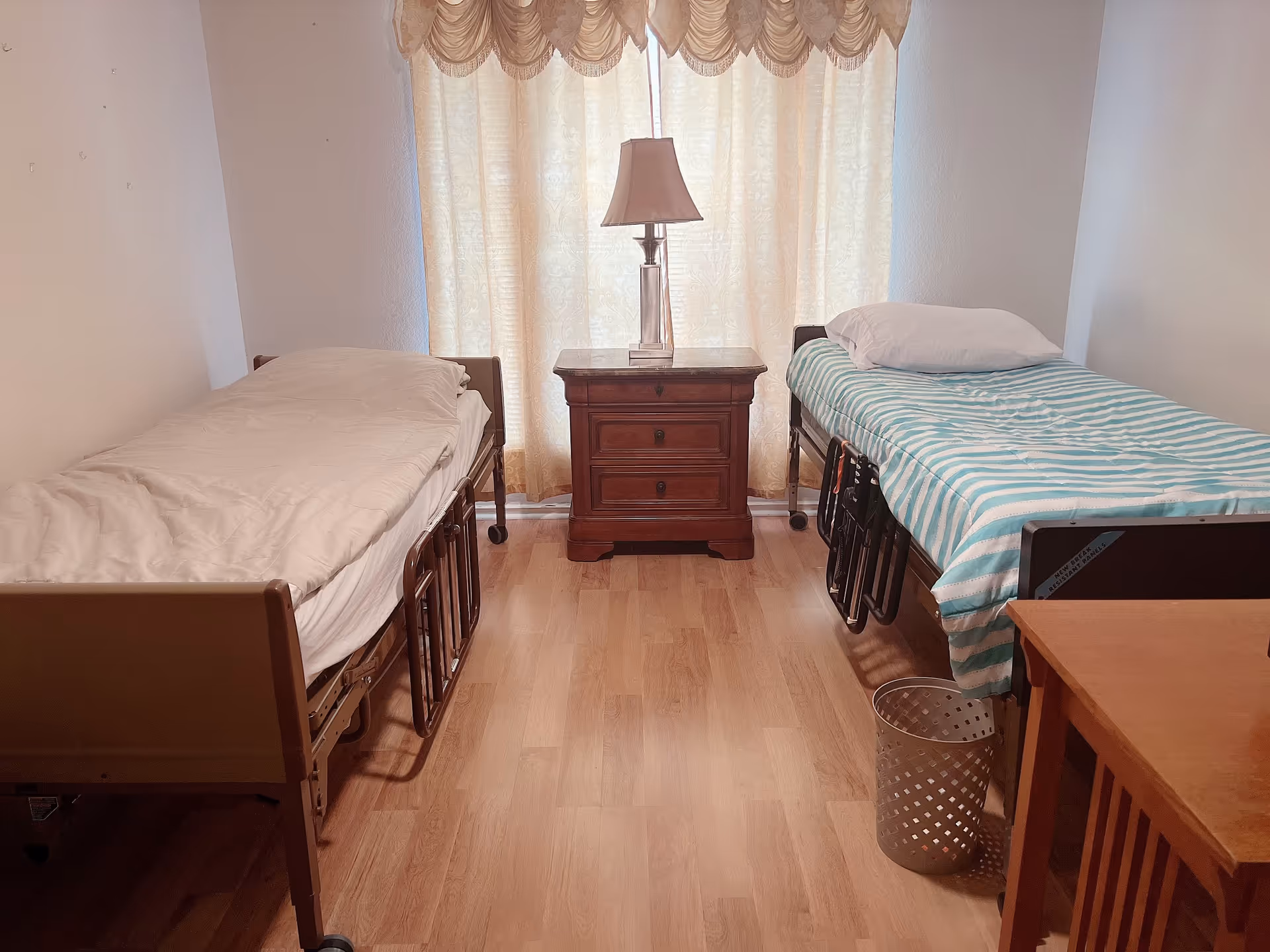 Two twin beds flank a central nightstand with a lamp in a shared bedroom.