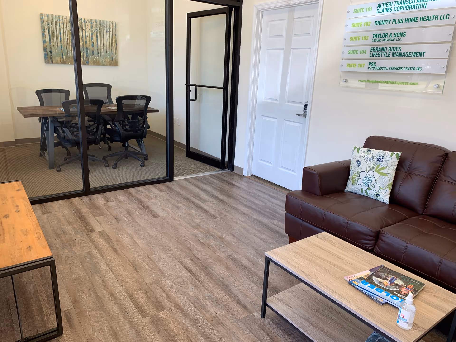 Interior common area with brown leather sofa, coffee table, and glass-walled conference room.