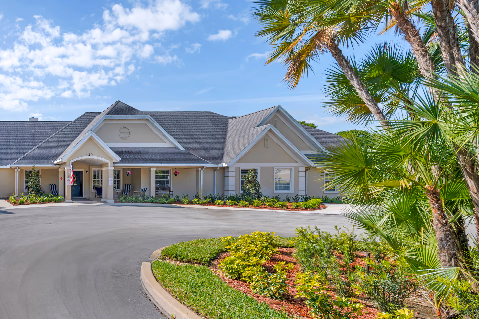Exterior view of Brookdale Vero Beach South Memory Care building with landscaped driveway and palm trees.