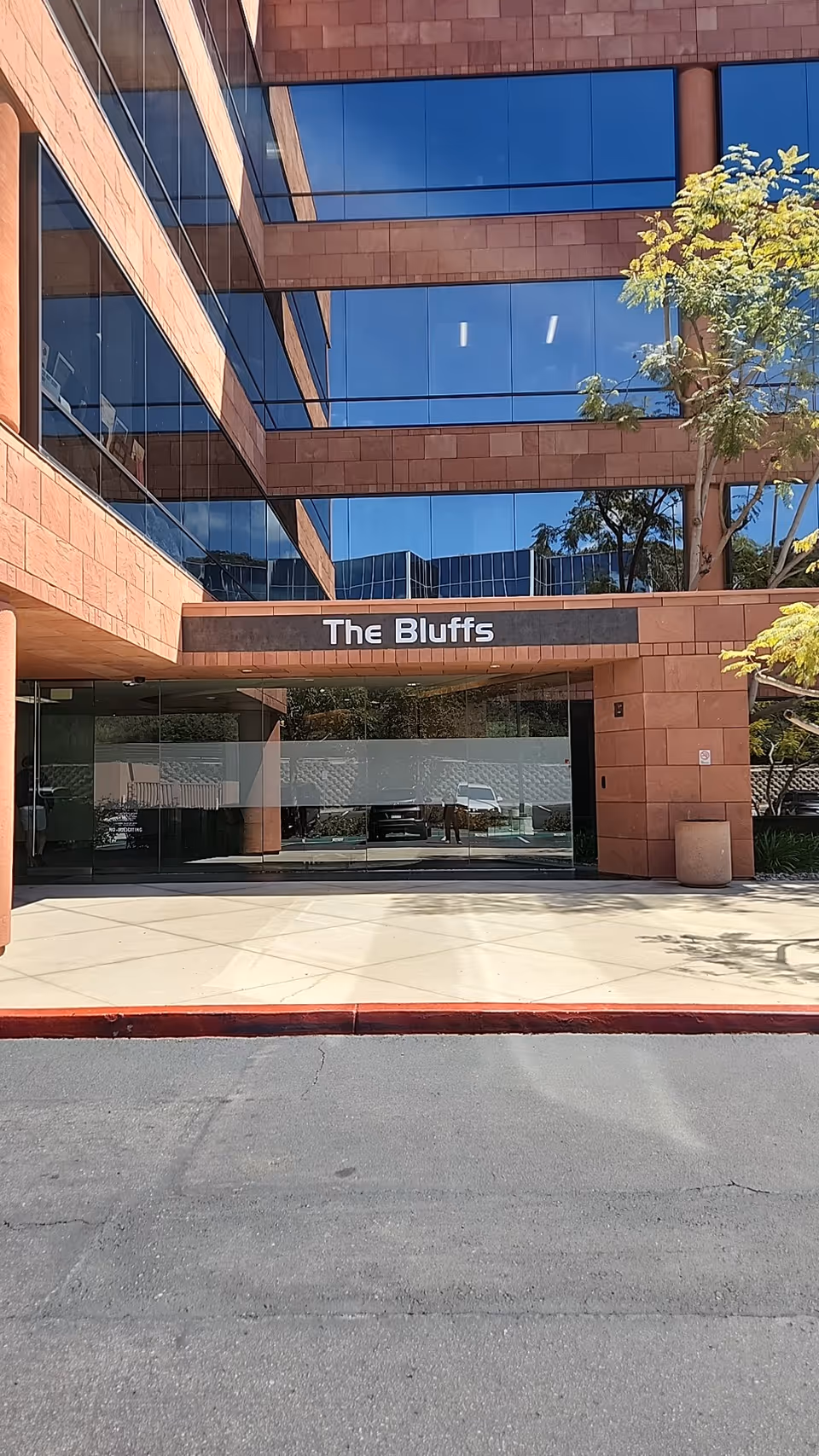Exterior view of a modern brick building entrance labeled The Bluffs with glass windows.