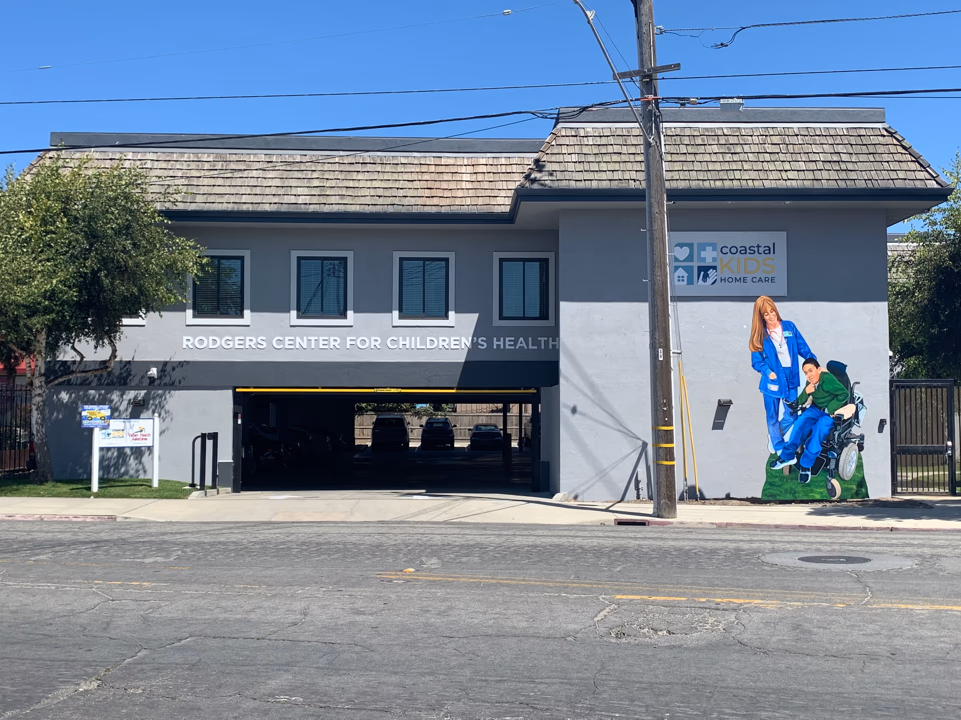 Gray two-story building with open driveway and Coastal Kids Home Care sign.