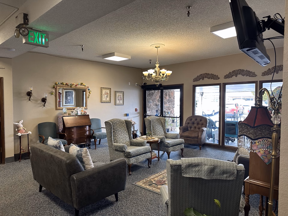 Cozy lounge area with sofas, chairs, chandelier, and glass doors to outdoor patio.