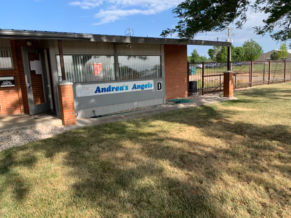 Exterior view of Andrea's Angels facility with sign, brick walls, windows, and fencing.
