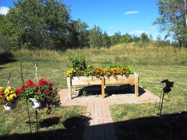 Outdoor garden area with wooden planter box and hanging baskets along a brick path in Medford.