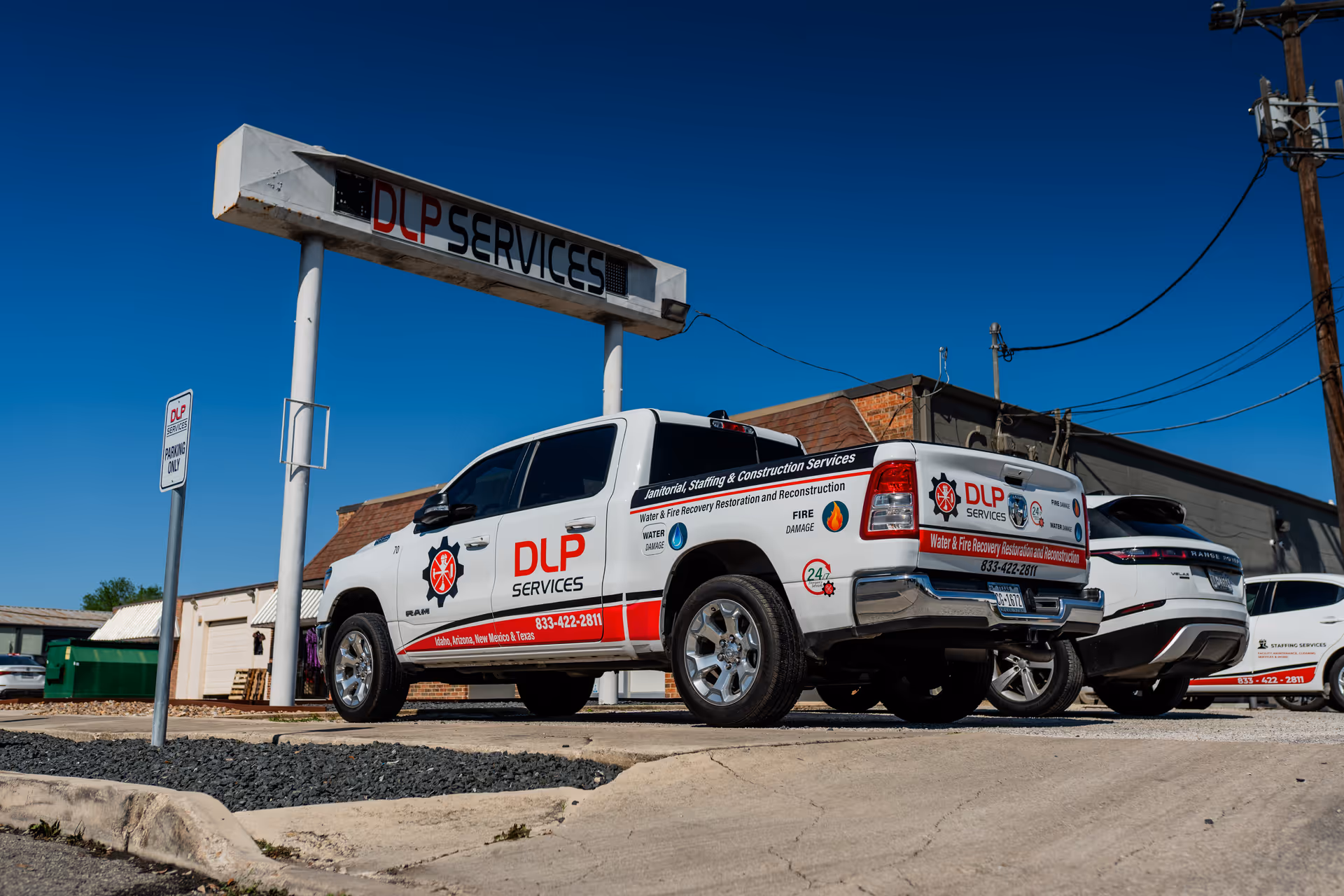 Exterior view of a DLP Services facility with company trucks parked outside.