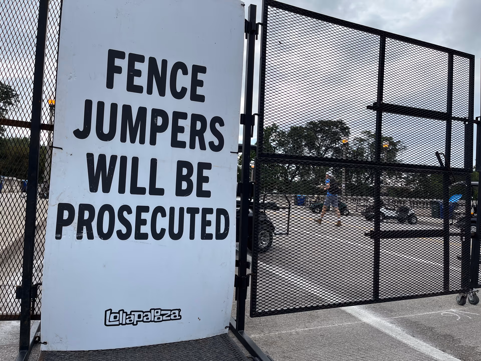 Outdoor gate with a large sign warning 'Fence Jumpers Will Be Prosecuted'.