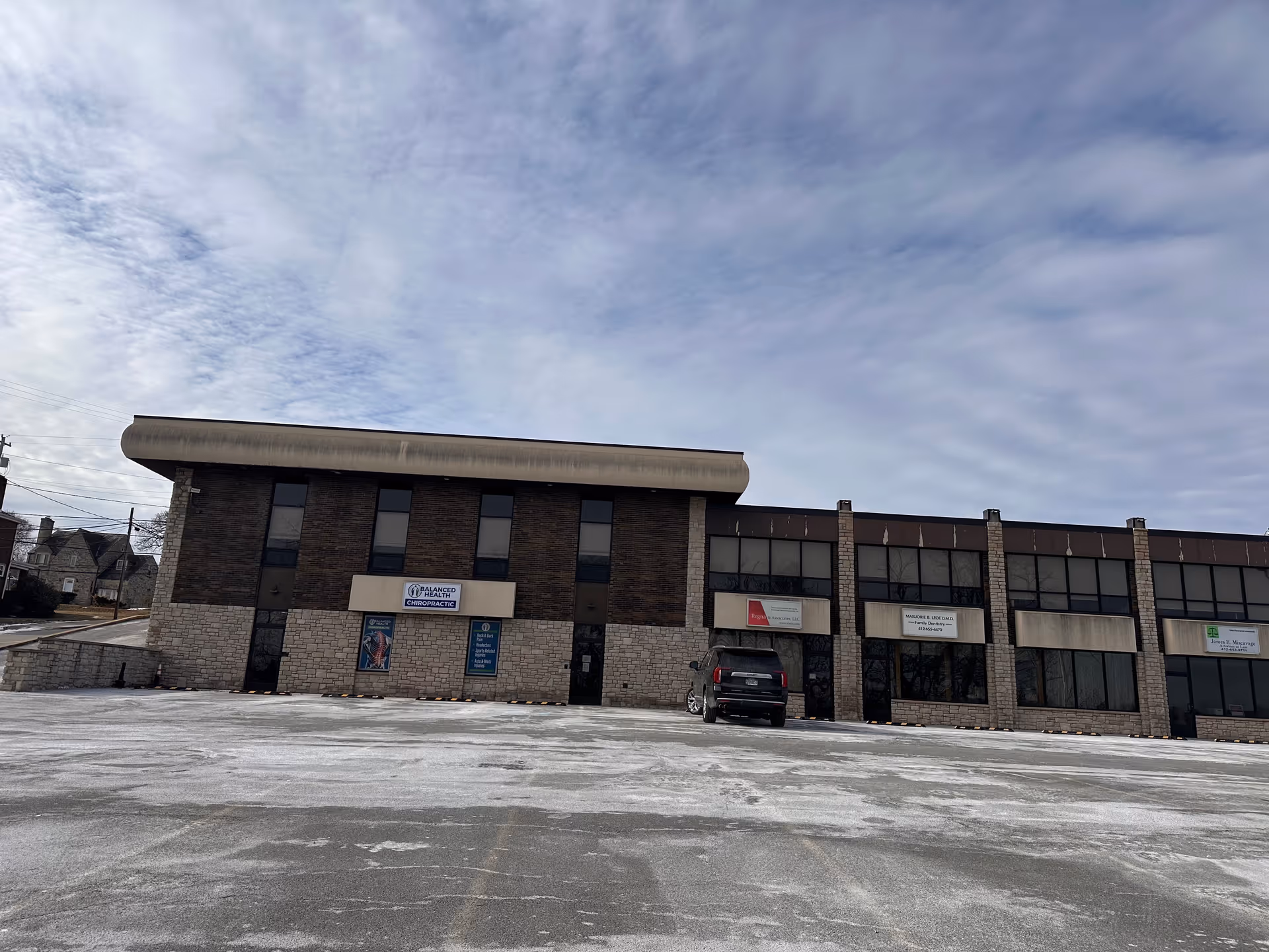 Exterior view of a two-story brick facility with a parking lot and cloudy blue sky.