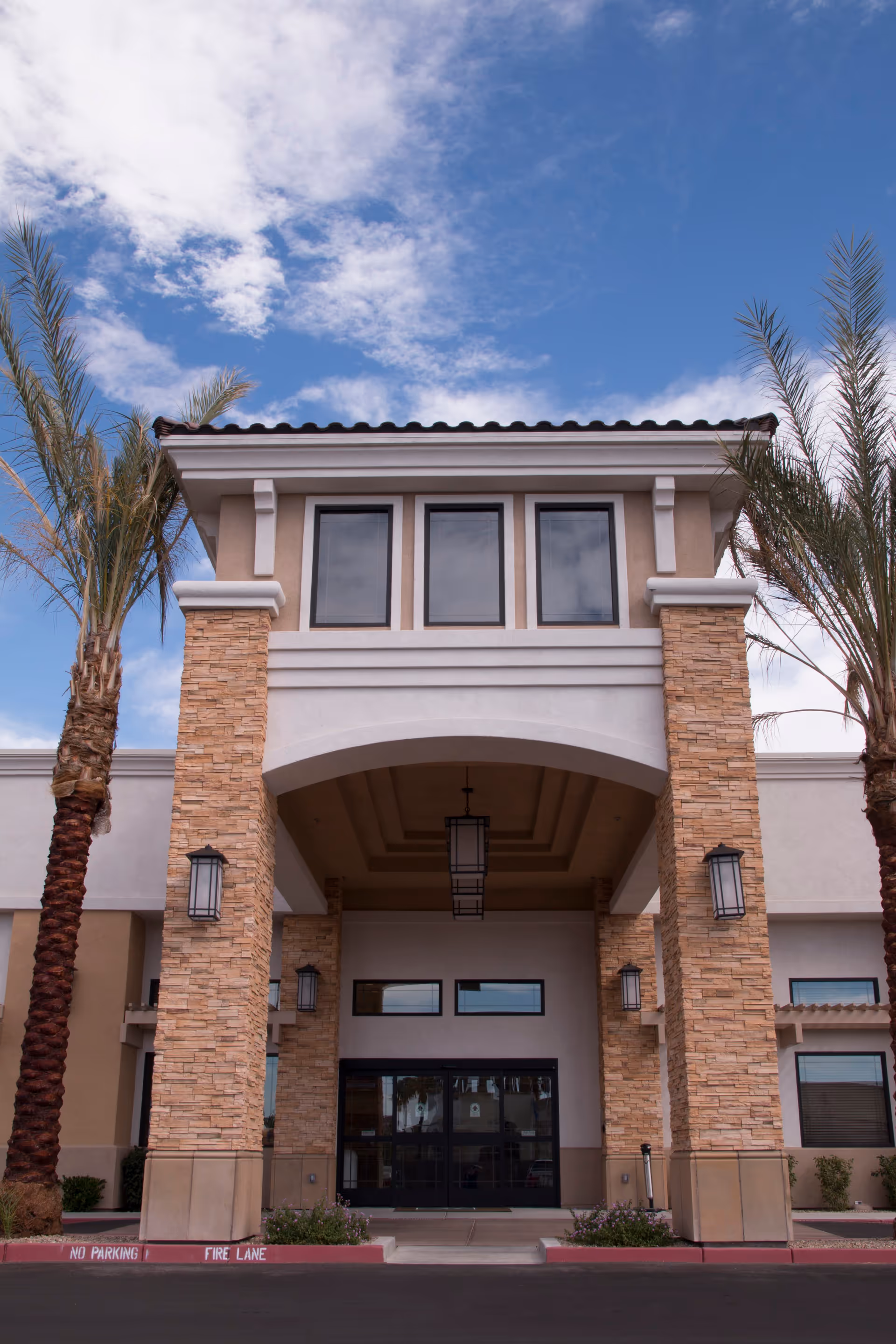 Exterior view of Skye Canyon Post Acute entrance with stone pillars and palm trees.