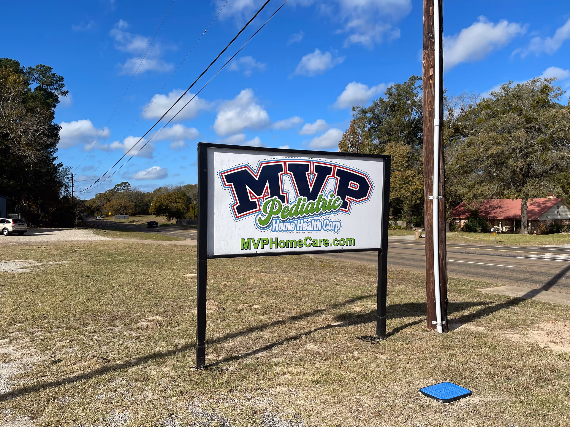 Outdoor road sign for MVP Pediatric Home Health Corp beside a two-lane street with blue sky