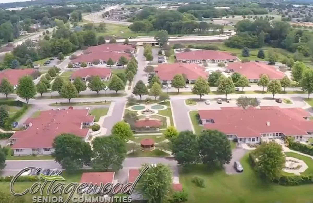 Aerial view of Cottagewood Senior Communities campus in Rochester with red-roofed buildings and green trees.