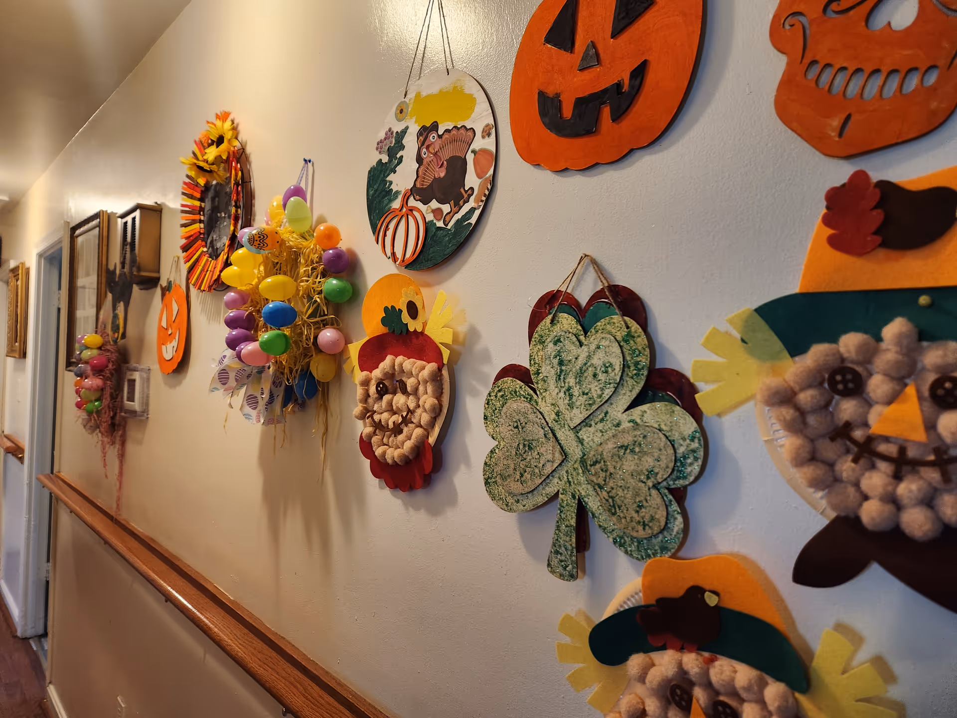 Hallway in a senior living facility decorated with colorful Halloween crafts on the wall.