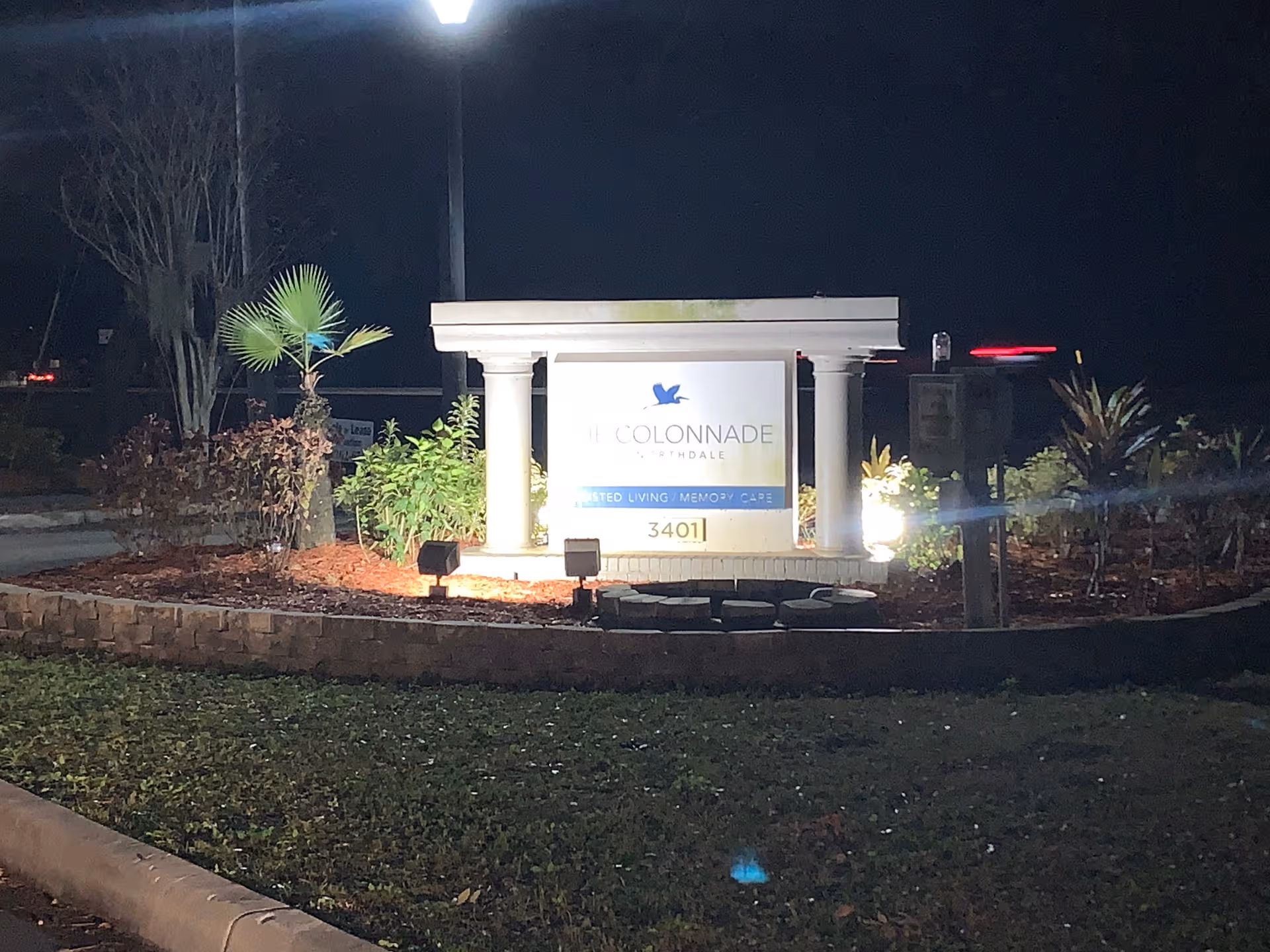 Night exterior of The Colonnade at Northdale entrance sign with landscaping.