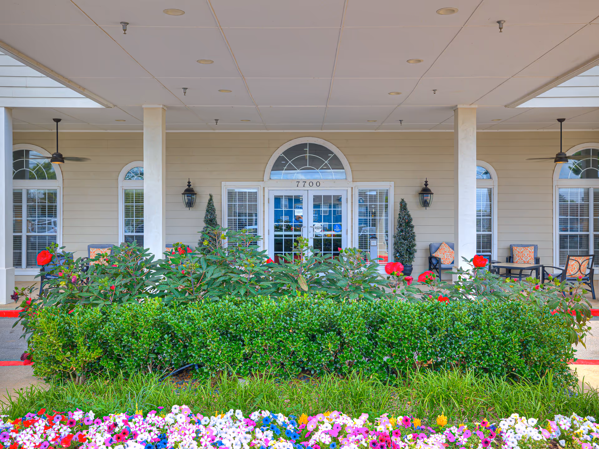 Front entrance of Hefner Mansions with arched window, greenery, and outdoor seating.