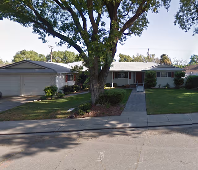 Front view of Valley Royale Care facility with a large tree and manicured lawn.