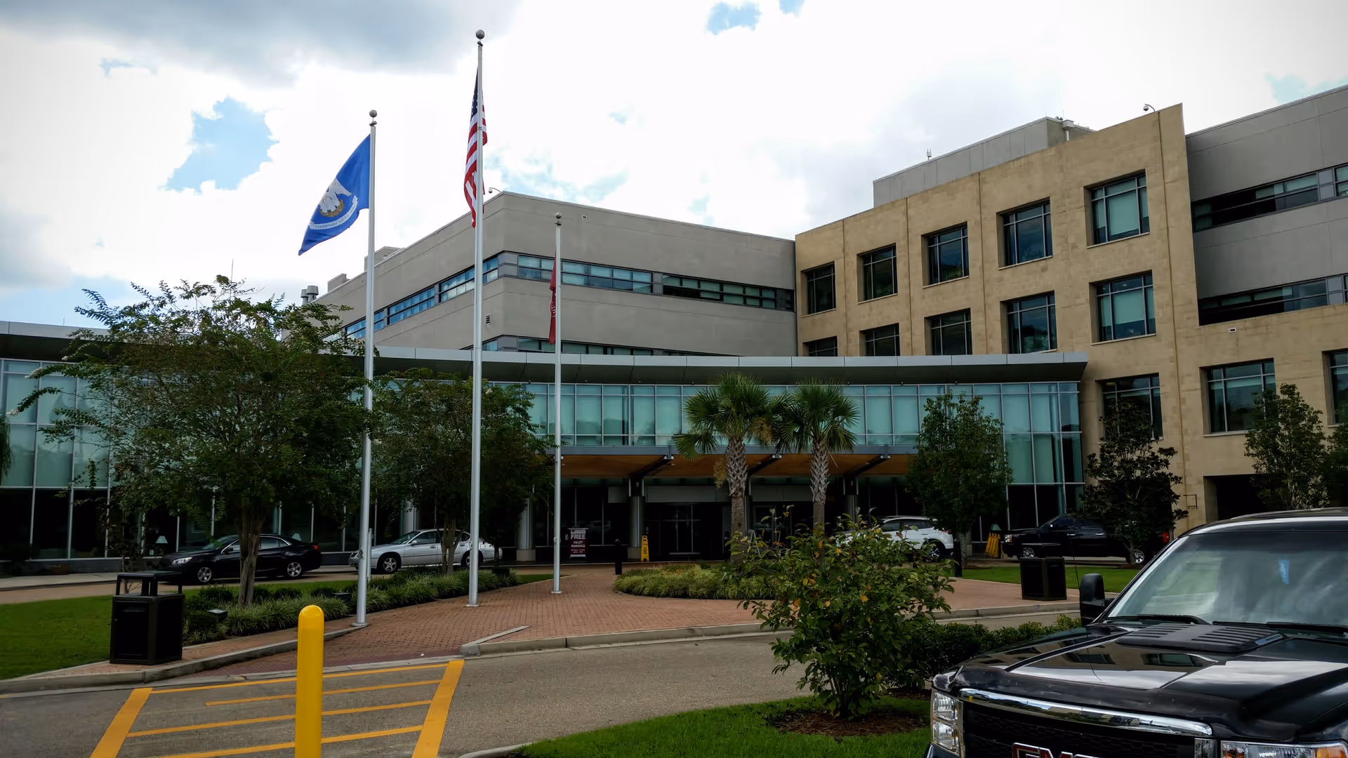 Exterior view of a modern medical facility with a glass entrance and flags.