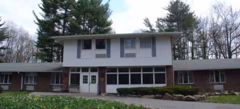 Exterior view of Elderwood Village at Greece building with brick base and central entrance.
