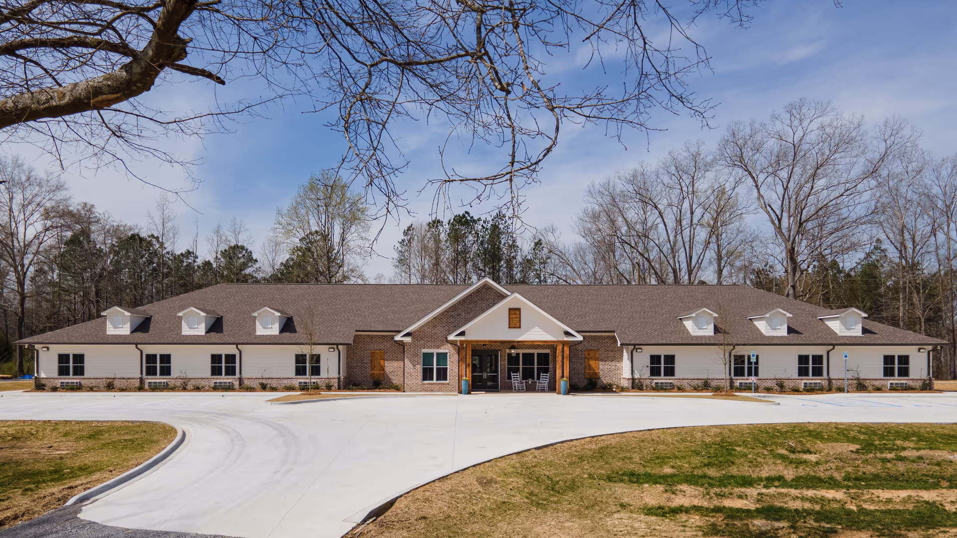 Single-story senior living facility with brick exterior, wide entrance, and circular driveway.