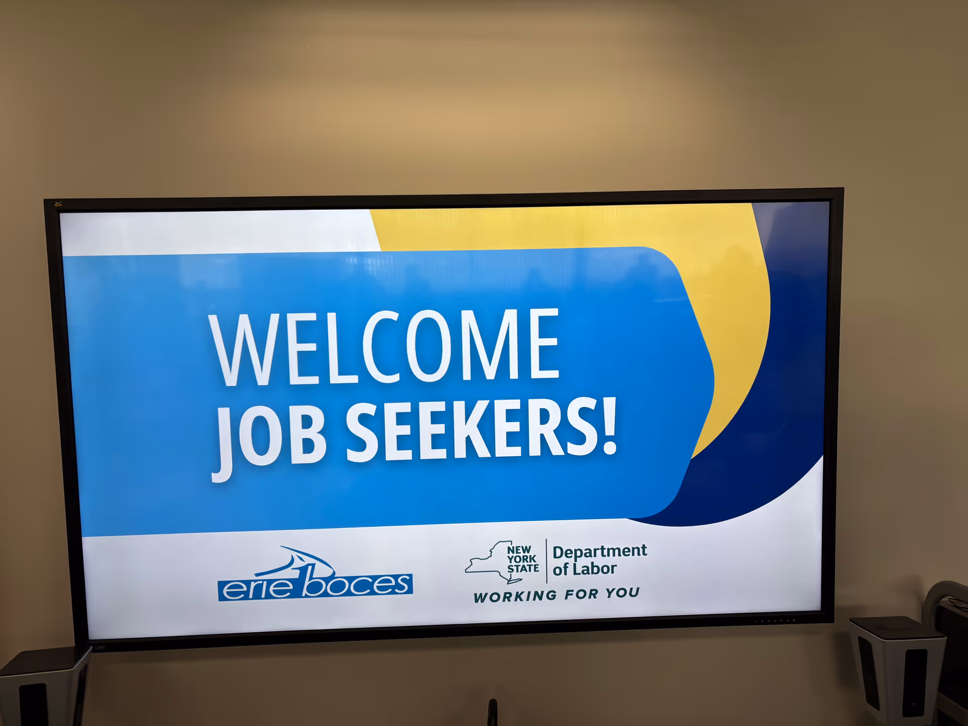 A large digital sign in blue and white welcoming job seekers inside Aurora Home Care, Inc.