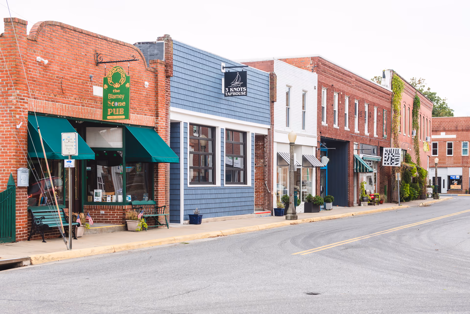 Row of brick storefronts along a small-town street with awnings.