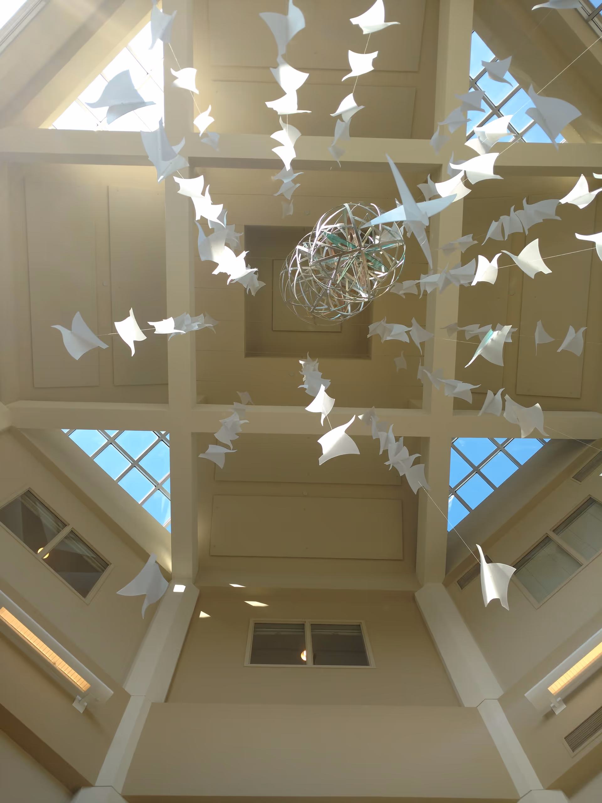 Indoor atrium at Eventide on Eighth Care Center with hanging paper cranes and sculpture.
