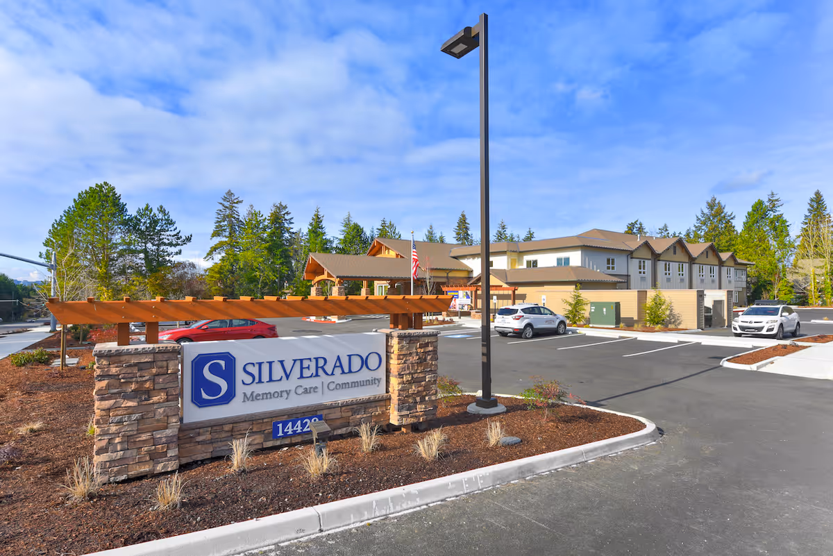 Exterior view of the Silverado Memory Care community building with its entrance sign and parking lot under a blue sky.