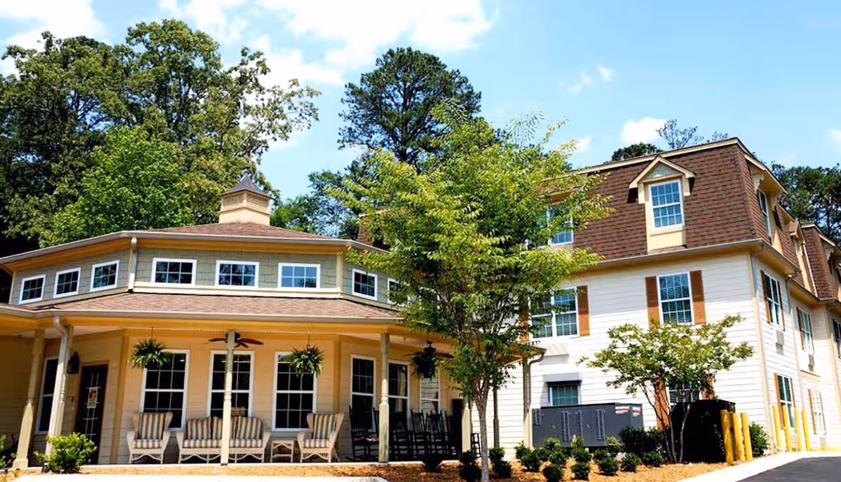 Exterior view of Highlands Senior Living Norcross building with porch and trees.