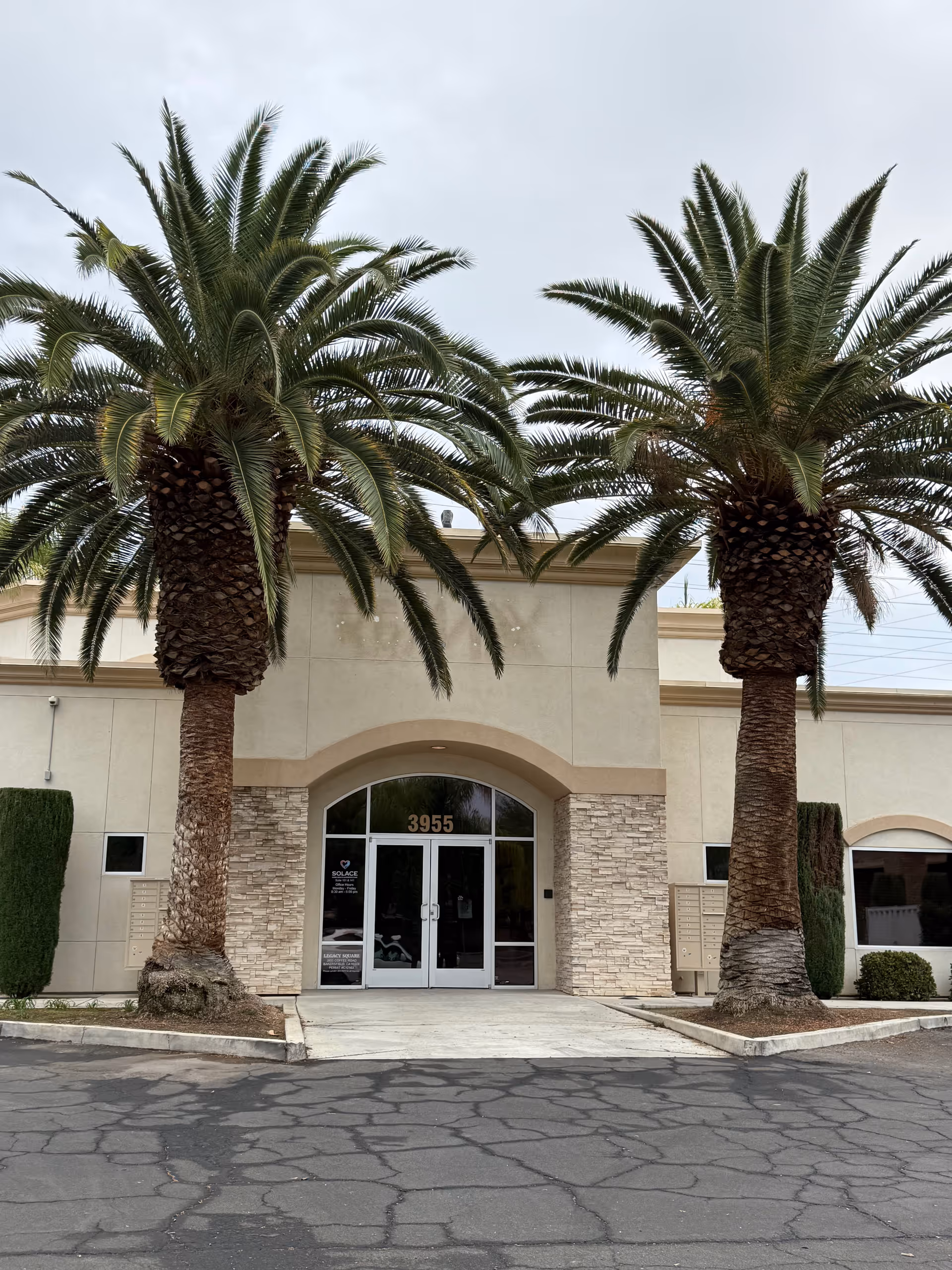 Front entrance of Solace Home Health and Hospice Care, 3955, with two palm trees.