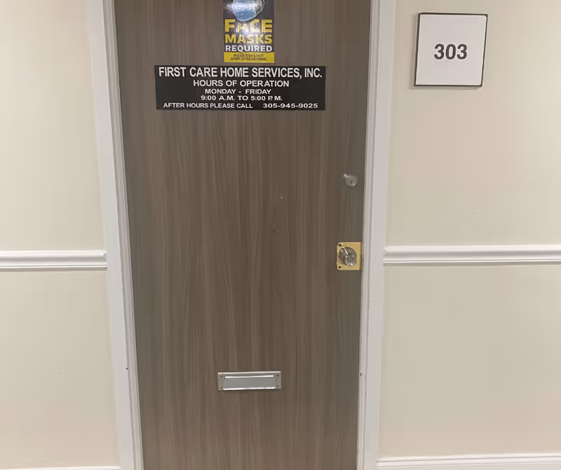 Wooden interior door with posted business sign and room number 303 on hallway wall.