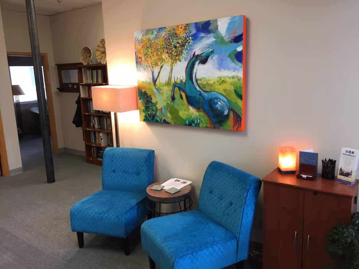 Two blue chairs flank a small round table in a cozy living area.