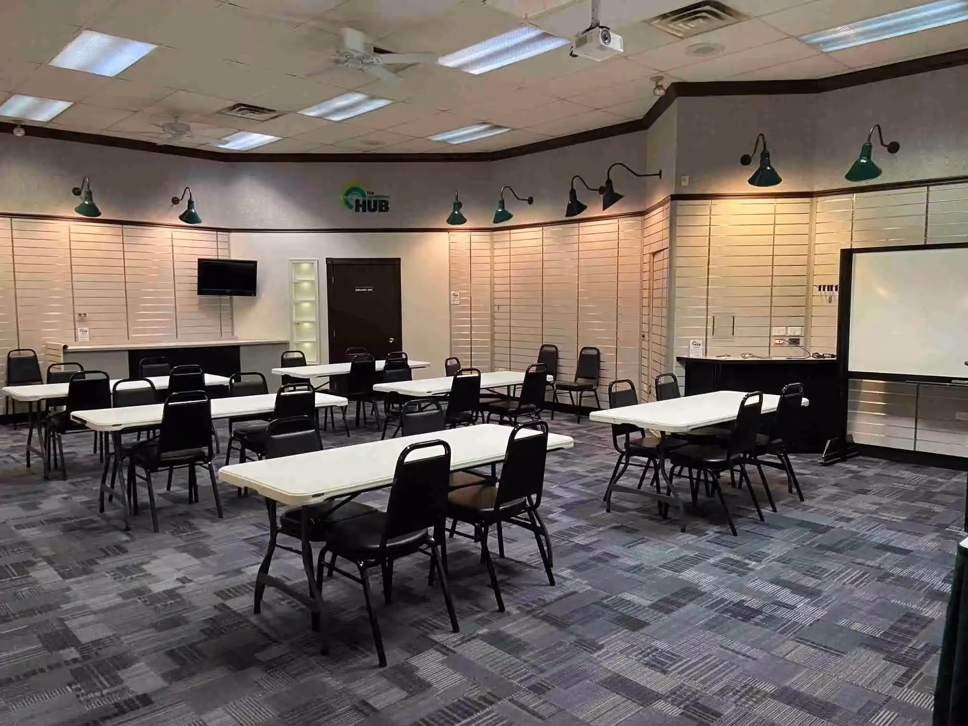Large community dining room with many tables and black chairs.