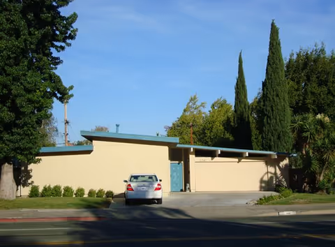 Exterior view of Willie Care Home II, beige facility with a blue door and a car.