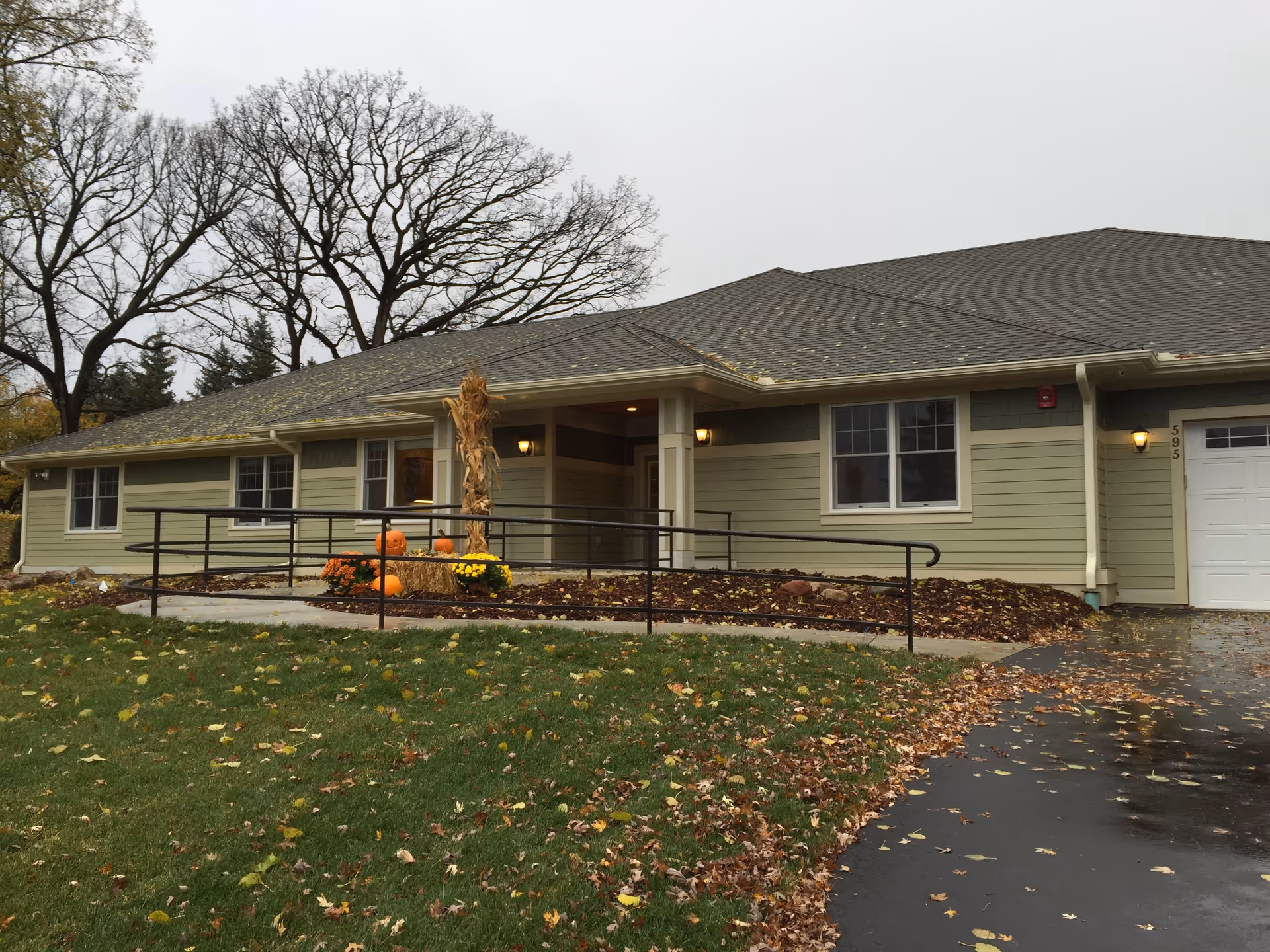 Front view of a single-story senior living facility with a ramp and pumpkins.