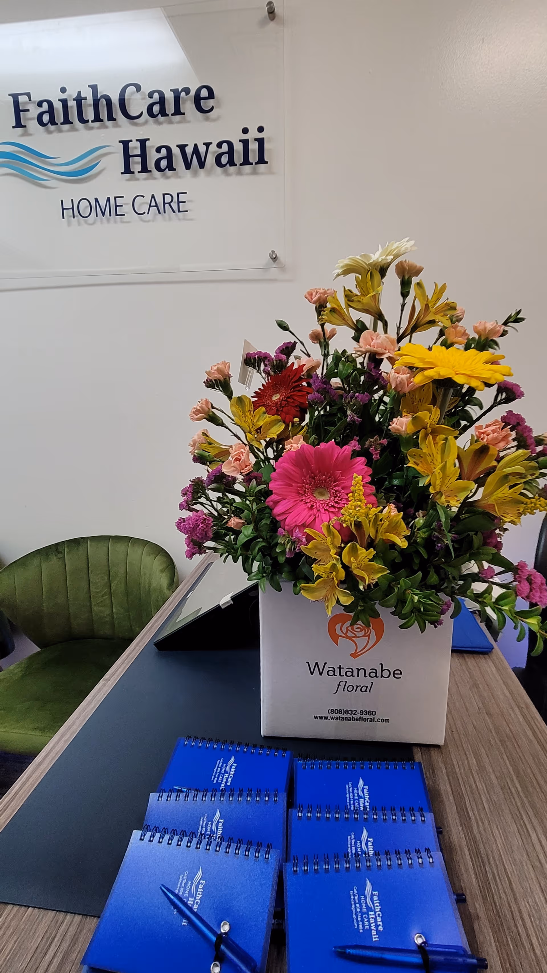 Interior reception area with FaithCare Hawaii Home Care sign and colorful flower arrangement.