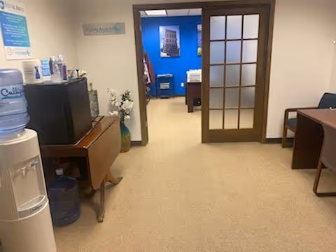 Indoor reception area with water cooler, desk, and glass-paneled door.