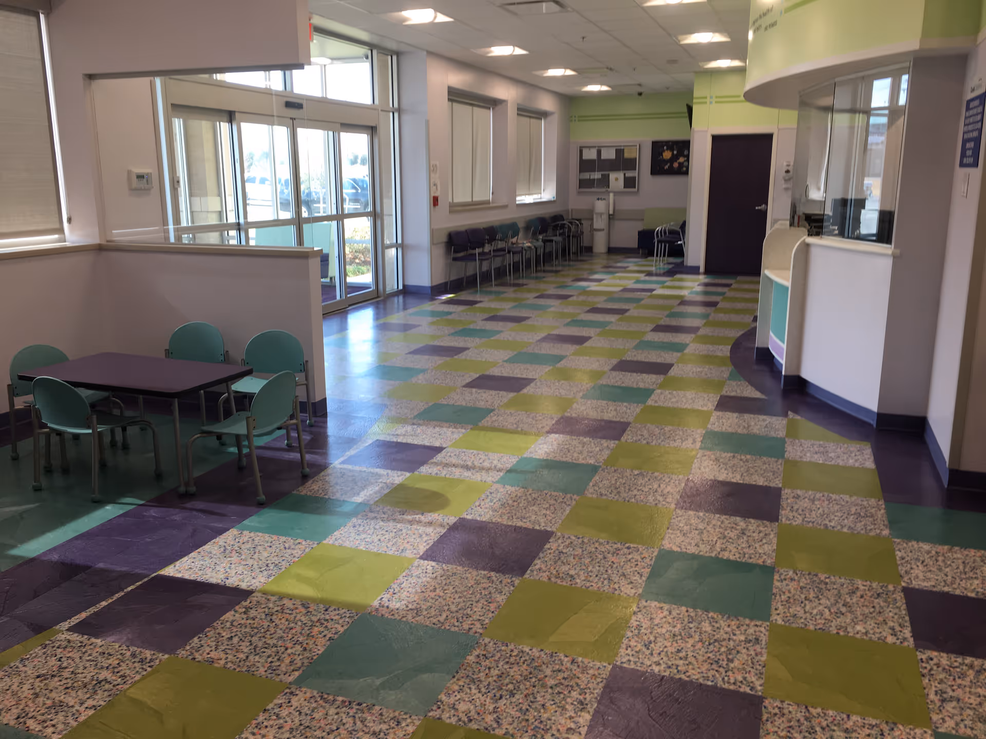 Colorful tiled lobby area with chairs, a reception desk, and glass entrance doors.