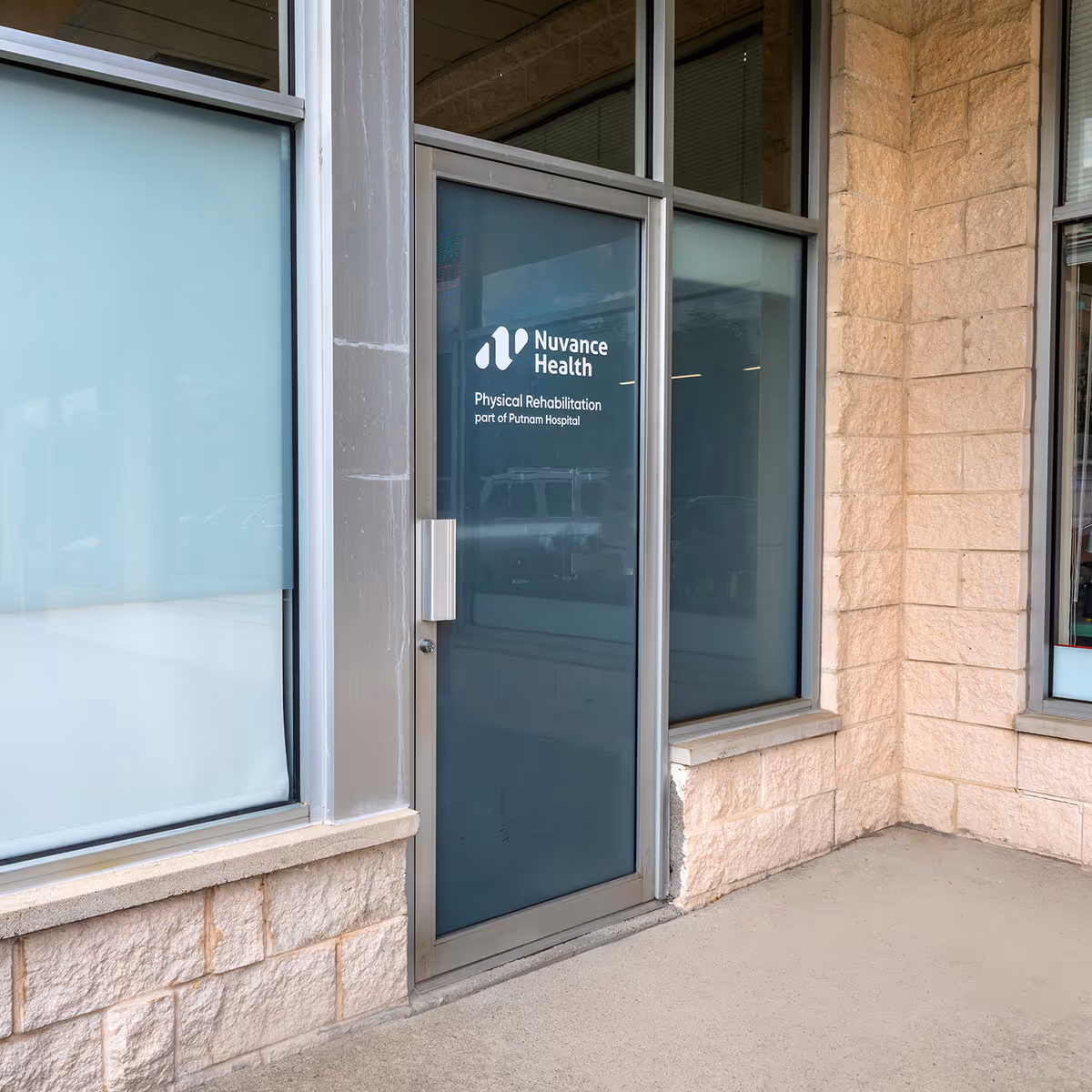 Glass door entrance with Nuvance Health Physical Rehabilitation signage on a stone exterior.
