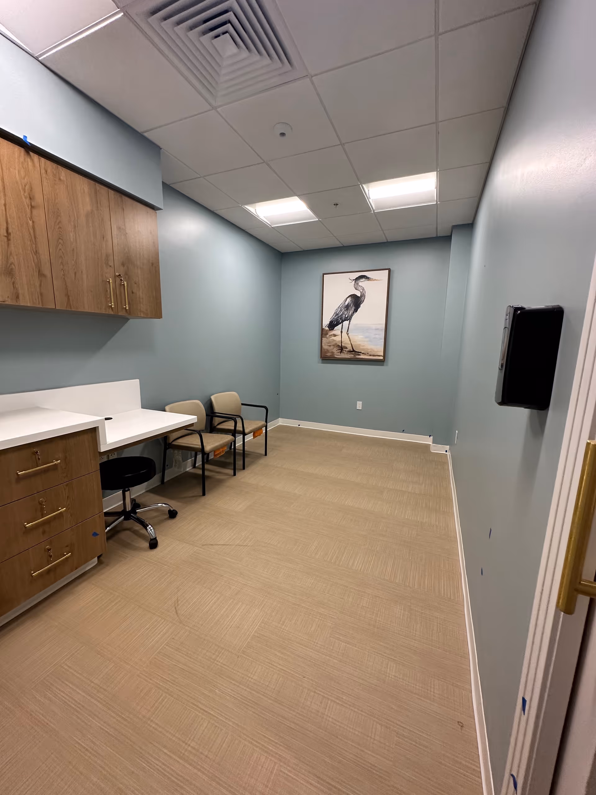A small staff area with cabinetry, seating, and a framed bird picture.