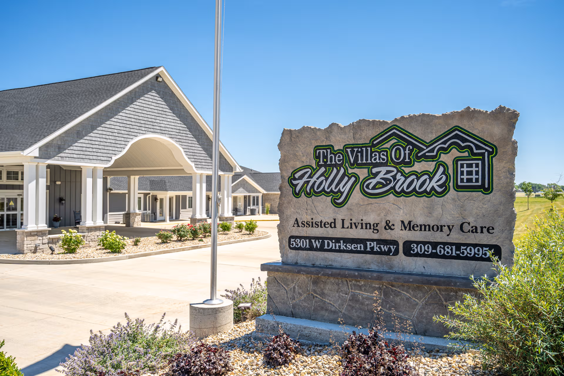 Exterior view of The Villas Of Holly Brook assisted living with its large entrance sign.