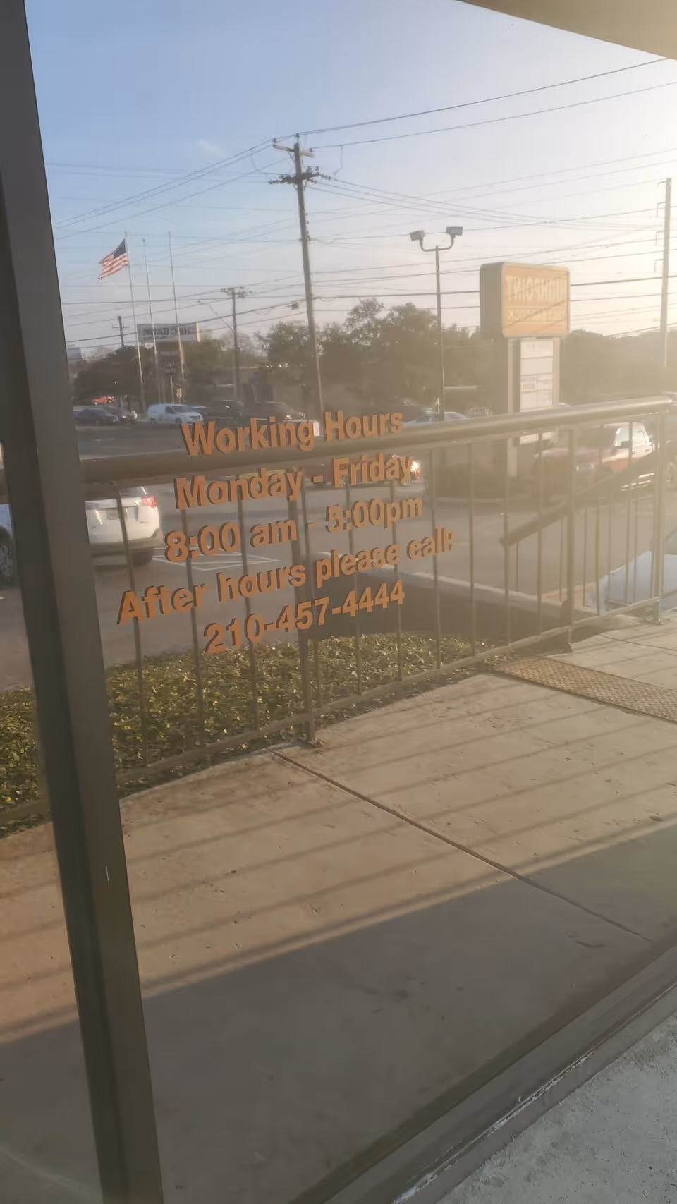 Orange text shows Working Hours on glass storefront with street view outside