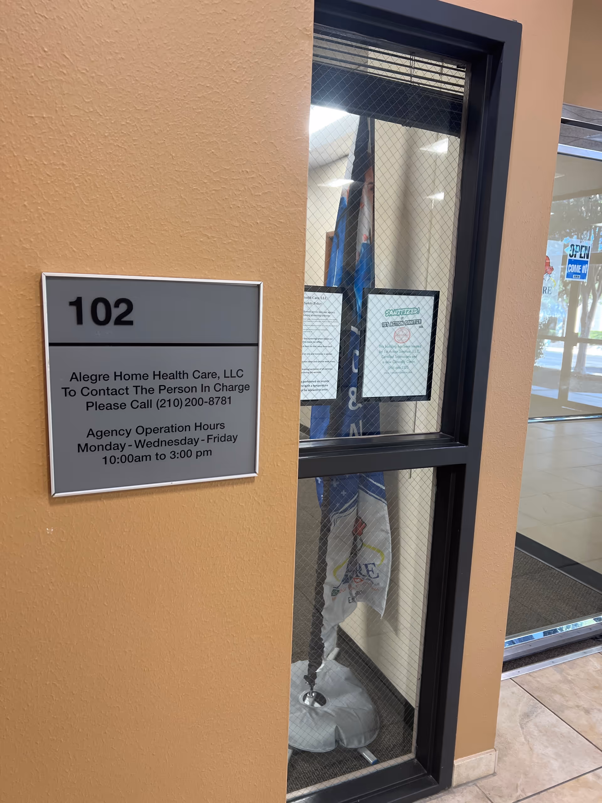 Interior wall with room 102 sign and a glass windowed office area by the entrance.