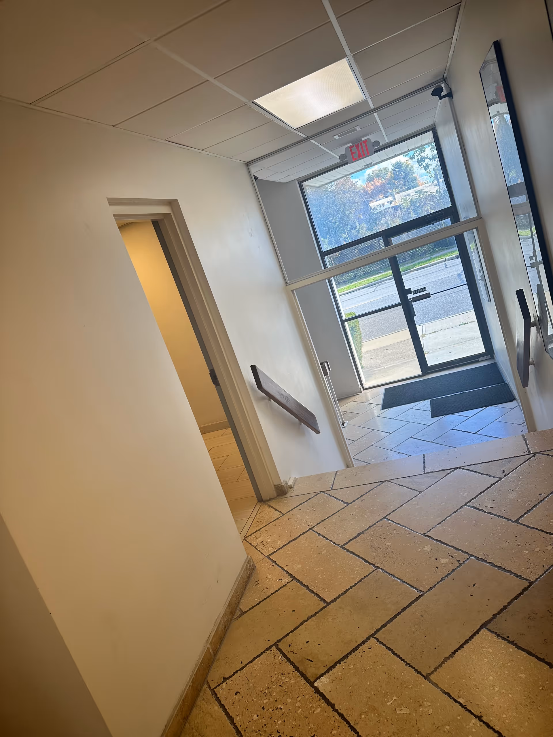 Interior hallway leading to glass exit door with tiled floor and windows