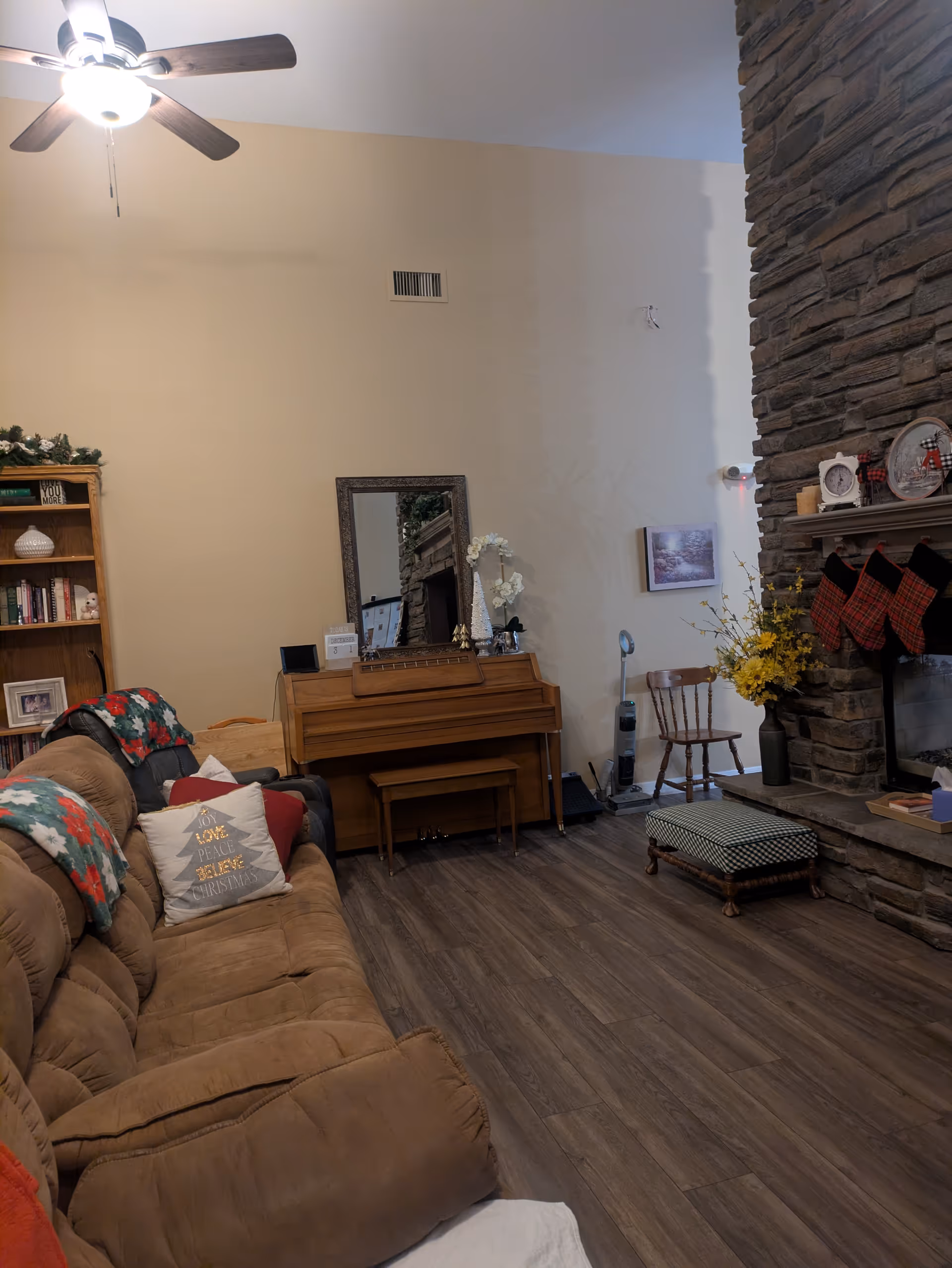 Cozy living room in Hope Haven with brown sofa, stone fireplace, and holiday decor.