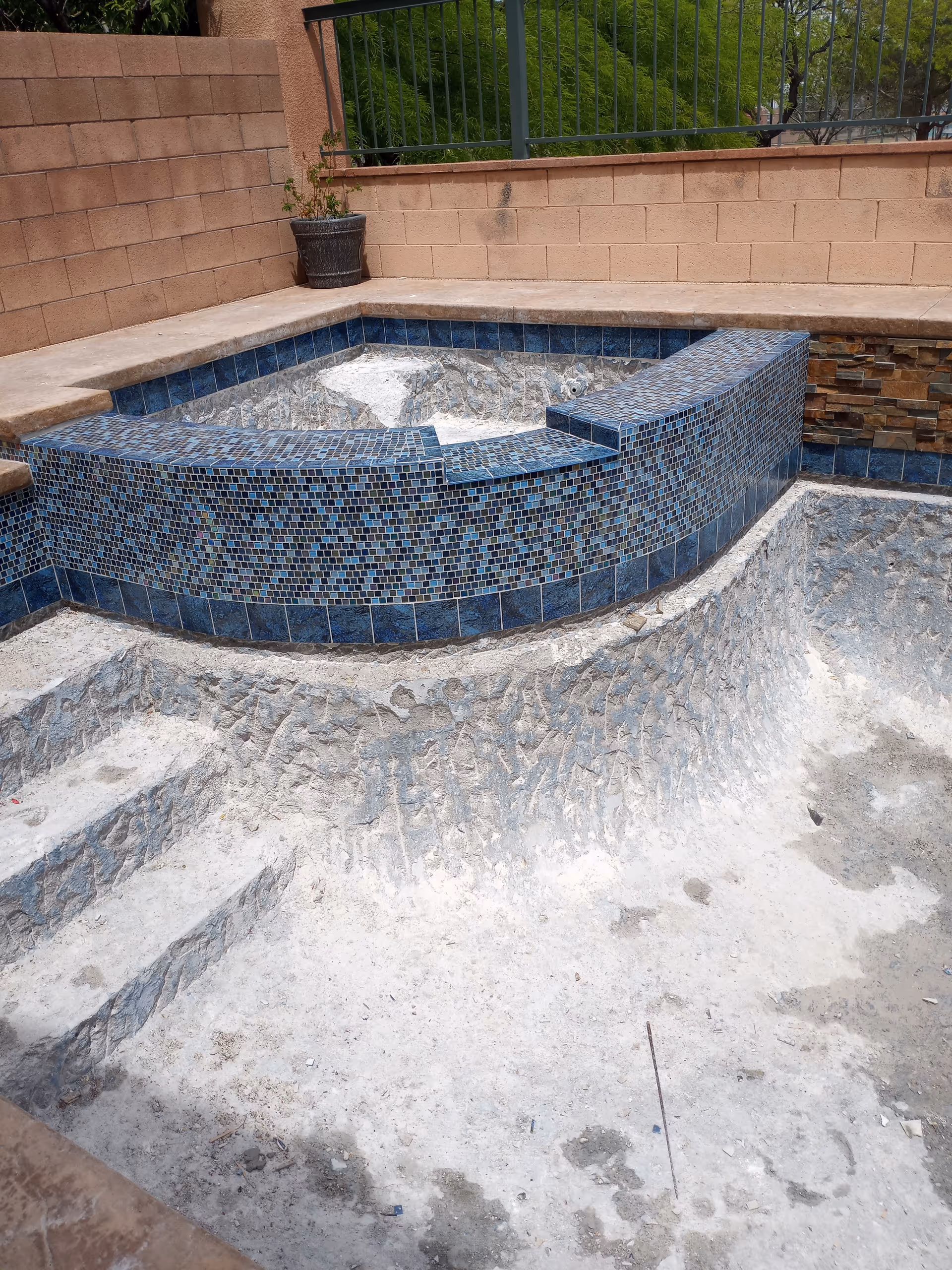 An empty tiled pool area with steps in an outdoor courtyard.
