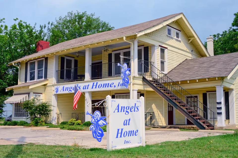 Exterior of Angels at Home, Inc. senior living facility, two-story with balcony and stairs.