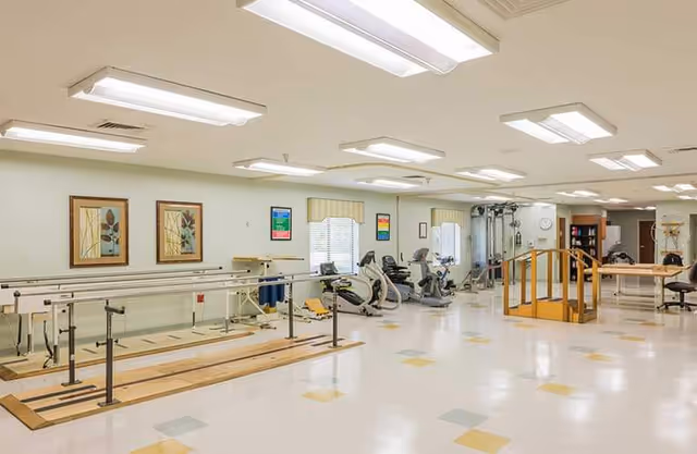 Bright interior rehabilitation gym with parallel bars and exercise equipment.
