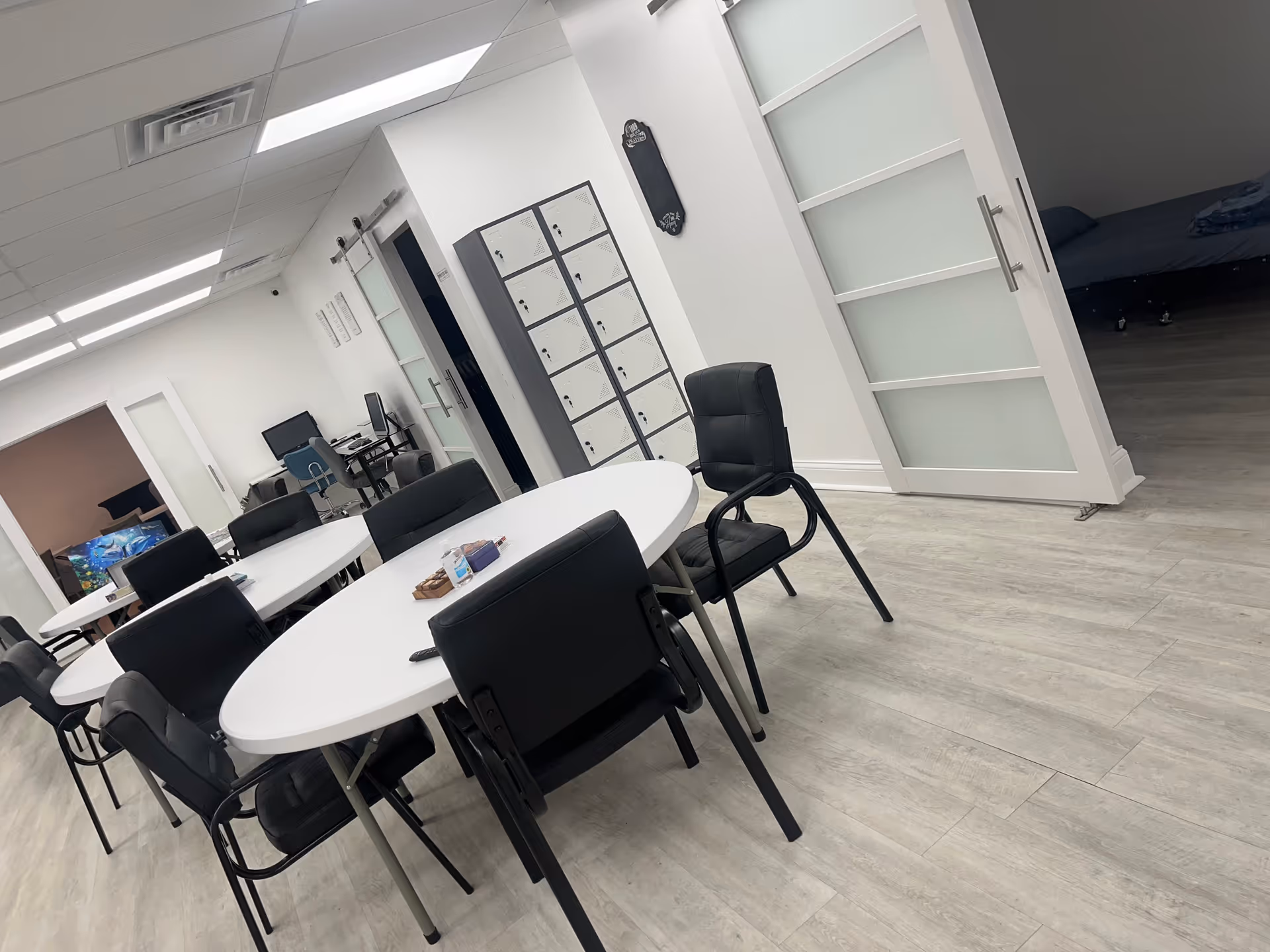 Bright modern interior with an oval white table, black chairs, and lockers.