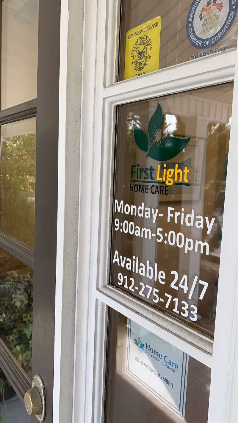 Glass entry door displays FirstLight Home Care Brunswick branding and hours.