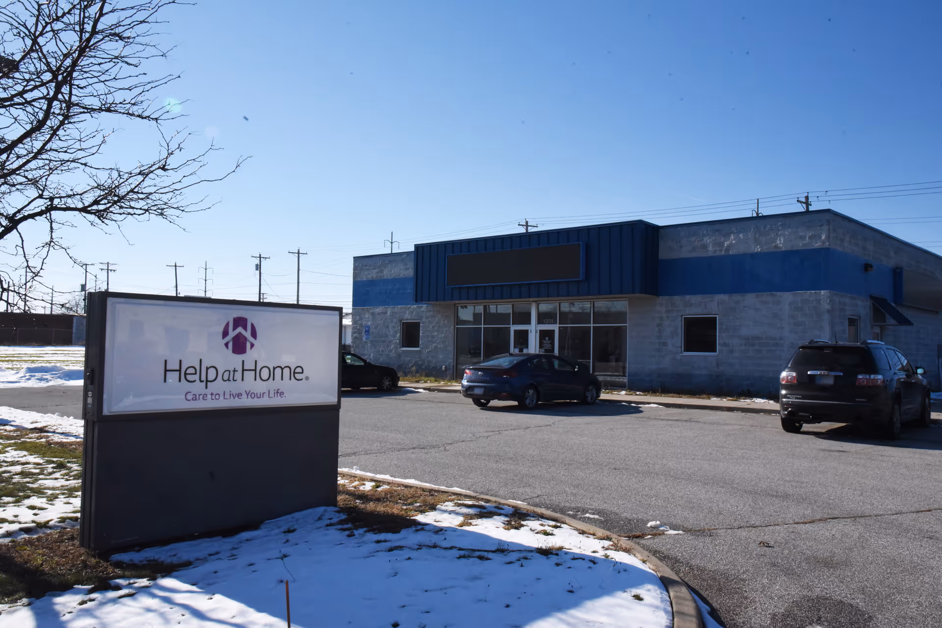 Exterior view of Help at Home facility with blue accents and parked cars.